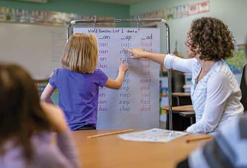 a teacher helping a student with an exercise on a classroom
