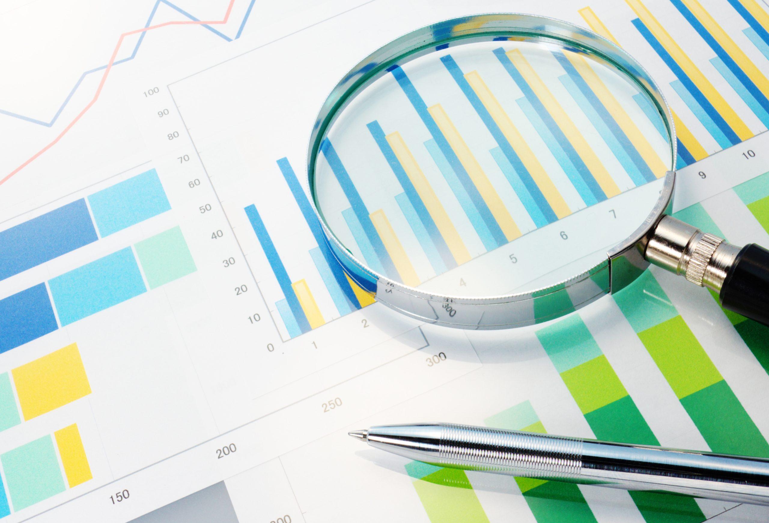 charts and graphs on paper with a pen and a magnifying glass