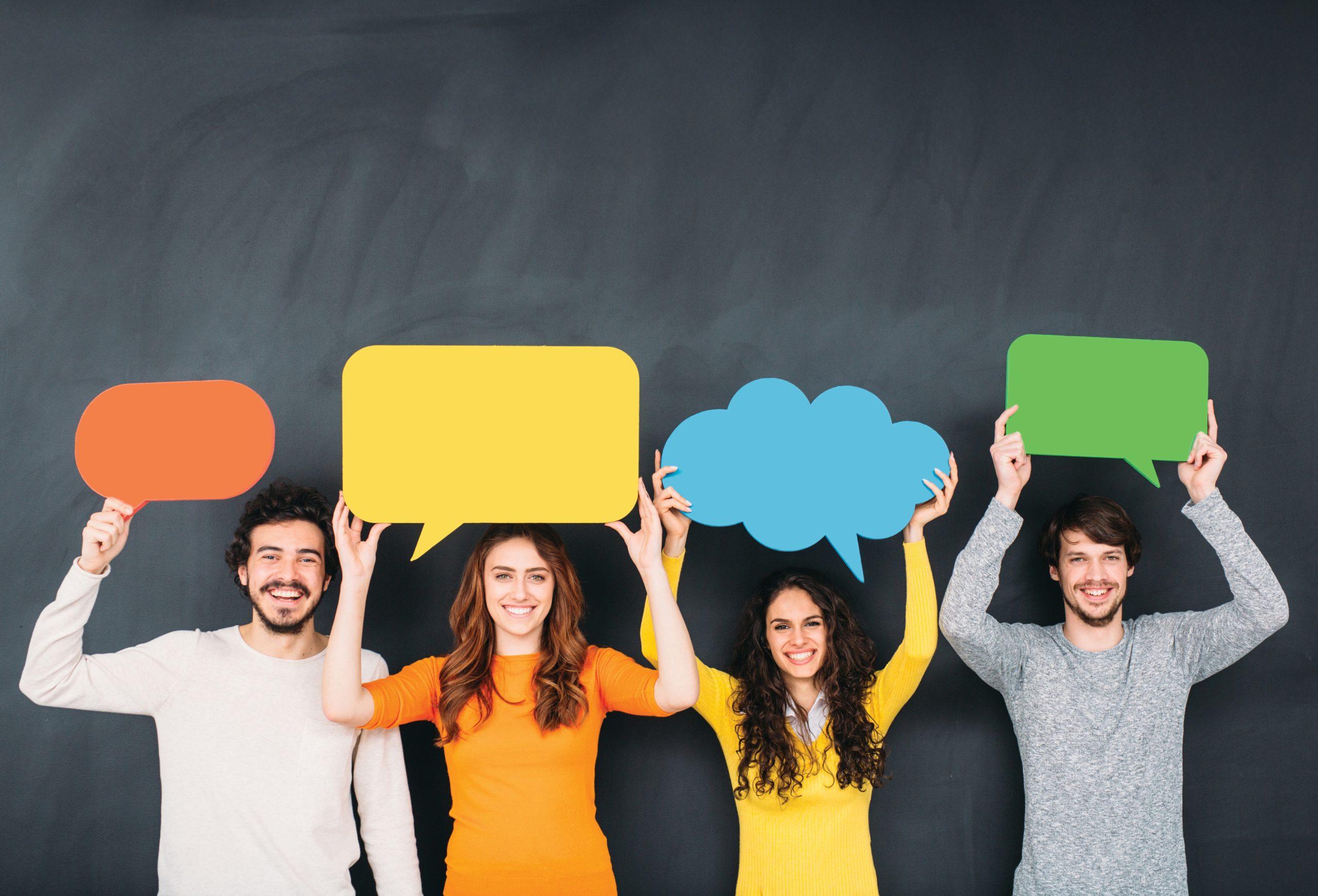 group of people holding cardboard colorful speech bubbles on top of their heads
