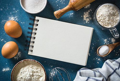 a kitchen table with a notebook for recipes and ingredients for cooking