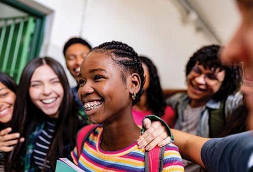 students gathering around a fellow classmate congratulating her