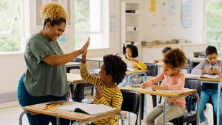 teacher high-fiving a student in a classroom