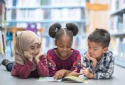 young students from different backgroungs reading a book on a library